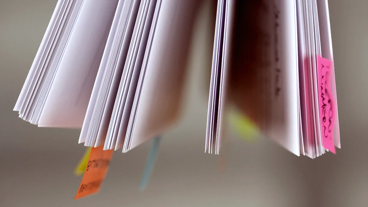 Pages d'un document imprimé feuilletées, marquées de plusieurs onglets adhésifs colorés