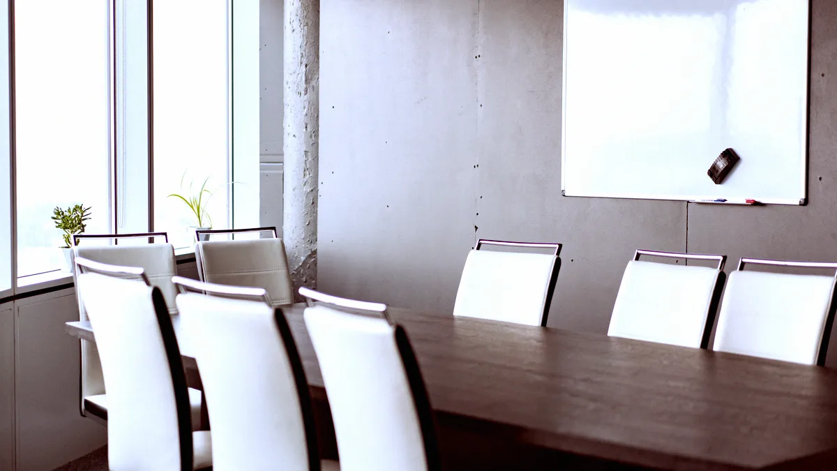 Salle de réunion vide, chaises blanches autour d'une table et tableau blanc effacé