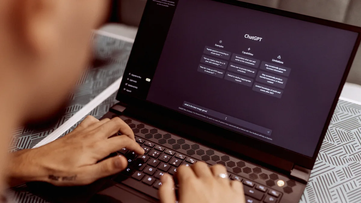 Personne de dos utilisant un assistant IA conversationnel ouvert sur un ordinateur portable