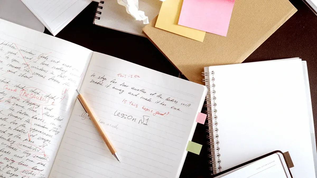 Cahier de brouillon corrigé au stylo rouge, crayon posé en travers, papier froissé en arrière-plan