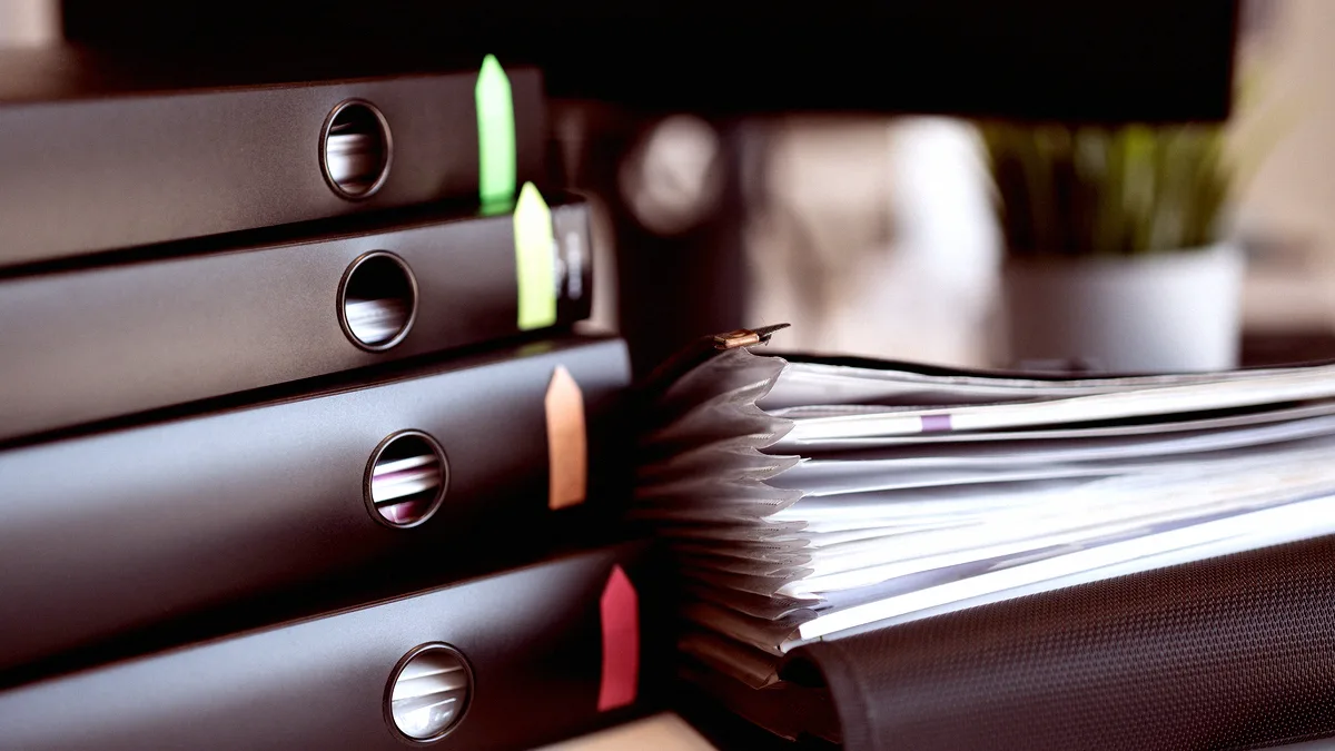 Classeurs à onglets de couleur et trieur à soufflets remplis de documents, posés sur un bureau