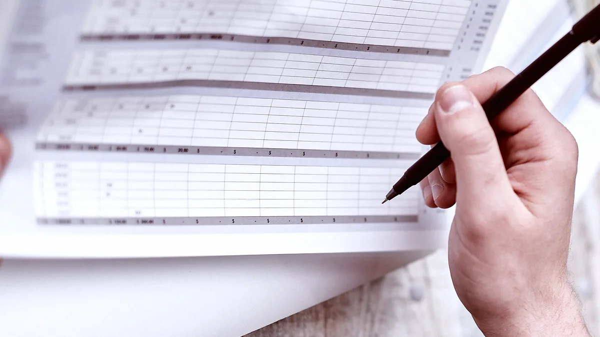 Main tenant un stylo au-dessus d'un tableau de budget imprimé