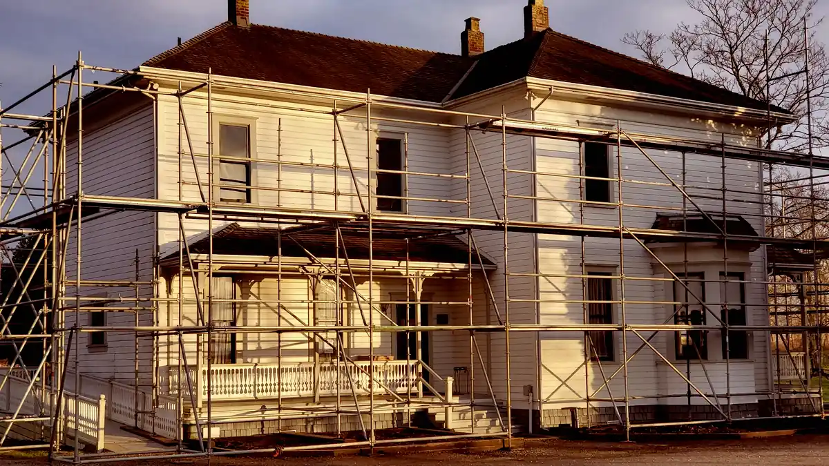 Maison ancienne entourée d'échafaudages, en fin de journée